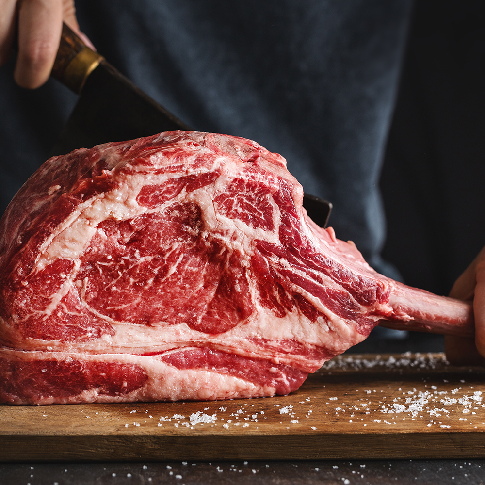 Butcher cuting fresh meat tomahawk steak