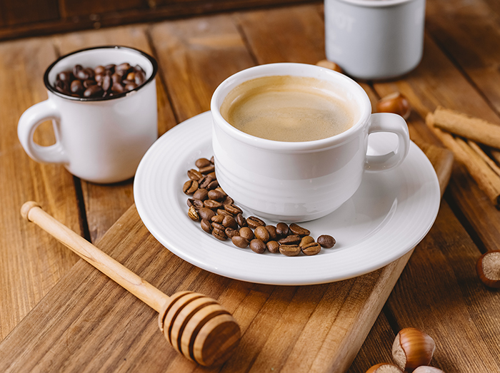 close up of coffee cup decorated with coffee beans placed on wooden serving board