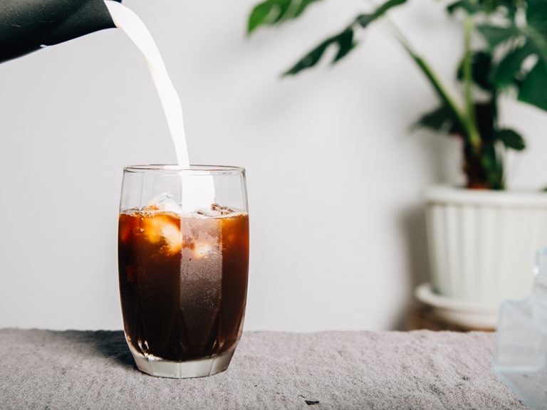 Summer drink poured milk make latte coffee with ice on a transpa