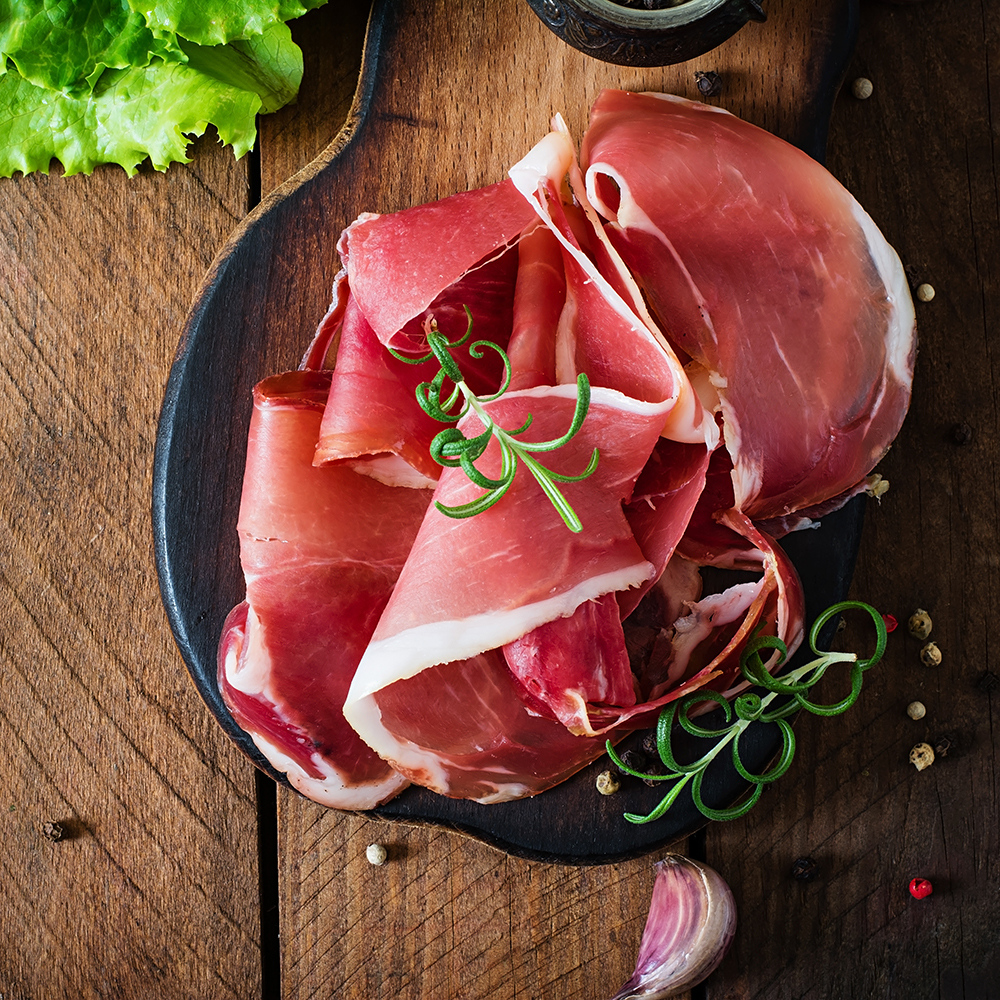 Grissini bread sticks with prosciutto on old wooden background