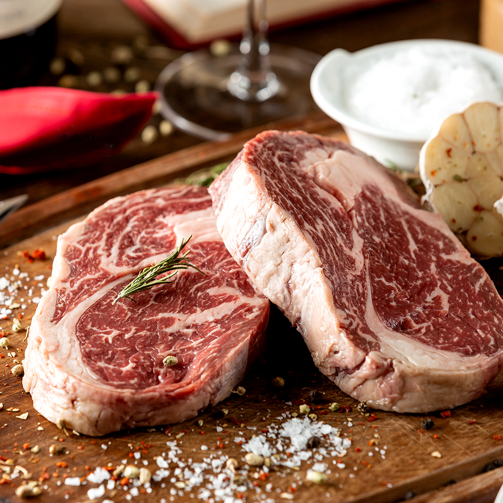close up of raw steak pieces garnished with salt and herbs