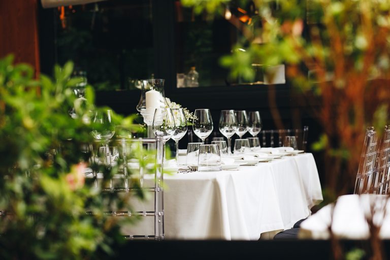 tableware Glasses, flower fork, knife served for dinner in restaurant with cozy interior