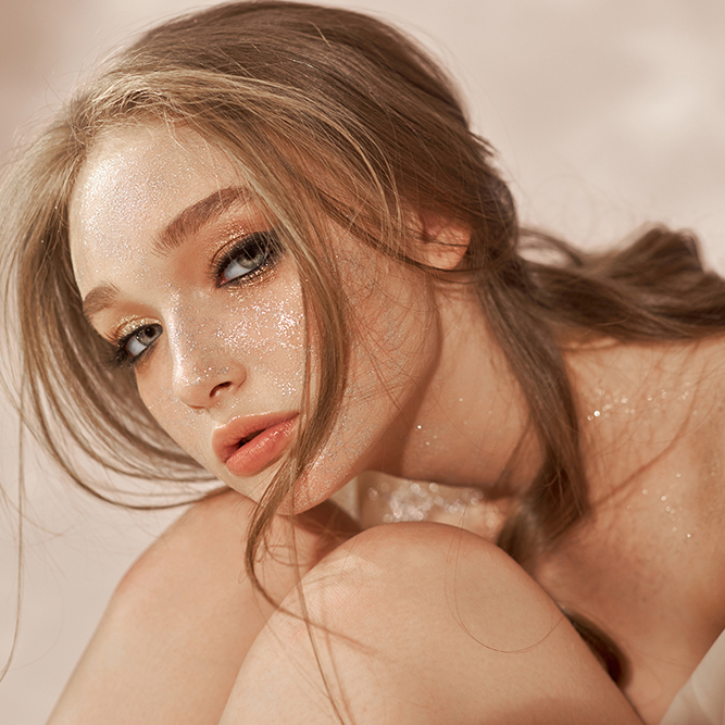Beautiful sexy woman sitting on the floor, cosmetics and makeup on the girl face and body