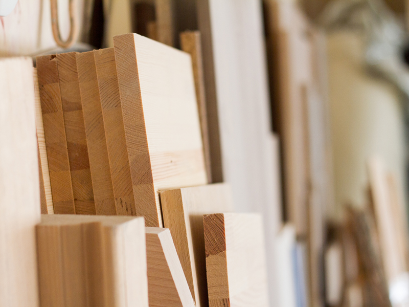 A wooden pillars and thick boards in the furniture workshop are ready to work joiner, selective focus